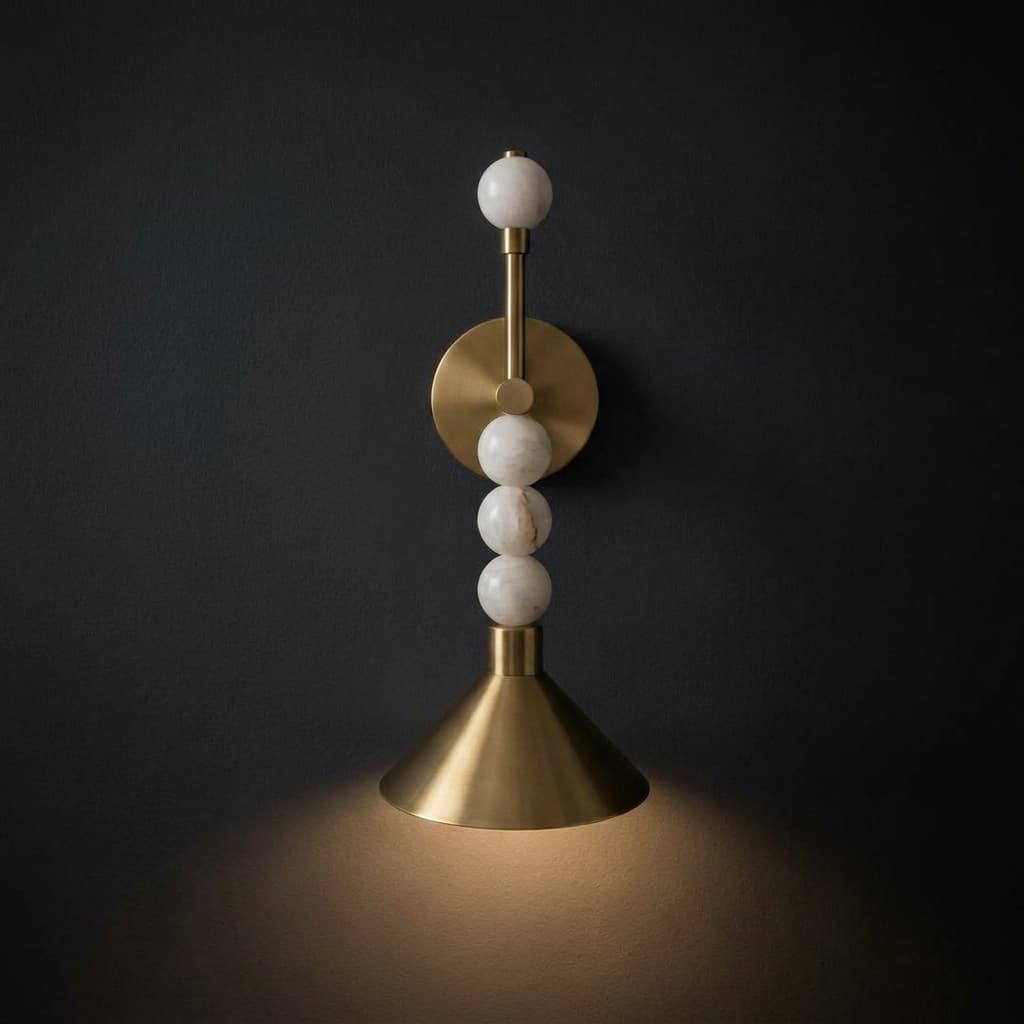 Modern alabaster and brass bedside wall sconce lit against a dark charcoal wall, showing stacked alabaster orbs and a conical brass shade (ArtLoka ALK-003)